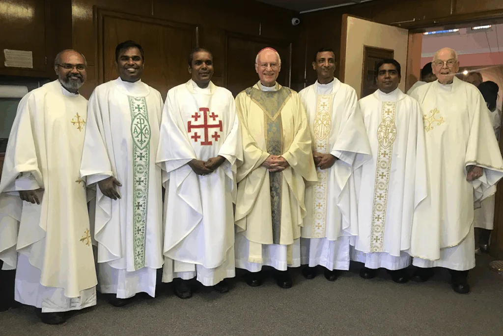 Priester und Seminaristen gemeinsam mit einem Bischof im liturgischen Gewand