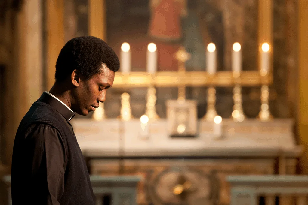 Ein Seminarist im Gebet vor dem kerzengeschmückten Altar einer Kirche